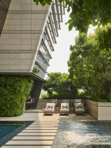 a patio with chairs and a pool in front of a building at Rosewood Bangkok in Bangkok