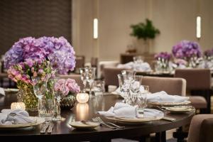a table with plates and vases of purple flowers on it at Rosewood Bangkok in Bangkok