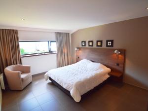1 dormitorio con 1 cama, 1 silla y 1 ventana en Luxurious Holiday Home in Profondeville Ardennes, en Bois-de-Villers