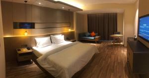 um quarto com uma cama grande e uma televisão de ecrã plano em Metropolo Jinjiang Weihai Railway Station em Weihai