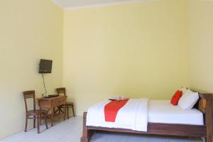 a bedroom with a bed and a desk and a television at RedDoorz Syariah near Balai Kota Probolinggo 2 in Probolinggo