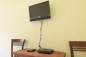 a tv hanging on a wall above a table at RedDoorz Syariah near Balai Kota Probolinggo 2 in Probolinggo