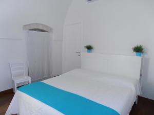 1 dormitorio con 1 cama blanca grande y 1 silla en Masseria Nonna Angela, en Putignano