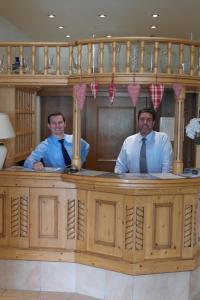 Zwei Männer in Krawatten stehen hinter einer Theke in der Unterkunft Hotel Habhof - Garni in Seefeld in Tirol