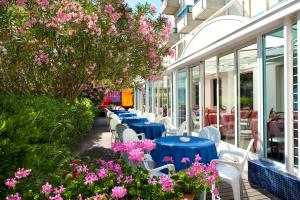 Hotel Felix في ريميني: صف من الطاولات الزرقاء والكراسي البيضاء والزهور