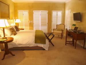 een slaapkamer met een bed, een bureau en een stoel bij Leighwood Lodge in Johannesburg