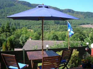 una sombrilla azul sobre una mesa de madera en Darroch View B&B, en Invermoriston