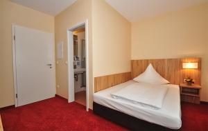 a bedroom with a white bed and a red carpet at Zellers Pension in Markt Erlbach