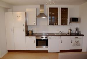a kitchen with white cabinets and a sink at Ferienwohnung Gipfelstürmer in Bolsterlang