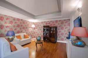 a living room with white furniture and red floral wallpaper at Hotel Caparena in Taormina
