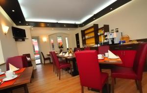 a dining room with red chairs and tables in a restaurant at Zellers Pension in Markt Erlbach