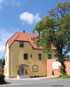 duży żółty budynek z czerwonym dachem w obiekcie Zellers Pension w mieście Markt Erlbach