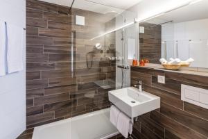 a bathroom with a sink and a shower at Central Swiss Quality Sporthotel in Davos