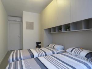 two beds in a room with white and blue stripes at Assago Forum Apartment in Assago