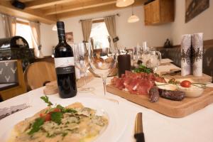 a table with a bottle of wine and a plate of meat at Mahlknechthuette Seiseralm in Alpe di Siusi