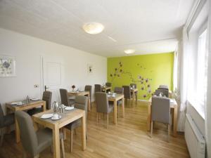 a restaurant with tables and chairs and a green wall at Pension Christiane in Sankt Kanzian