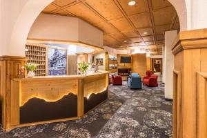 a lobby with a reception desk and red chairs at Central Sporthotel Davos in Davos +32 photos