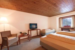 1 Schlafzimmer mit 2 Betten, einem TV und einem Stuhl in der Unterkunft Hôtel Bodenhaus in Splügen