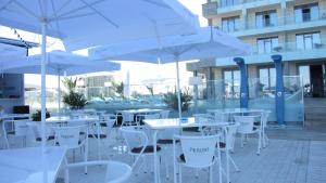 un grupo de mesas y sillas blancas con sombrillas en Frontal view by Twin Residence, en Mamaia