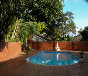 a swimming pool in a backyard with a brick fence at Hamilton Urban Farm Guest House in Pietermaritzburg