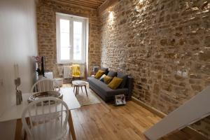 a living room with a couch and a brick wall at Hamac Suites - Studio Ainay 4 - Hyper centre Lyon in Lyon