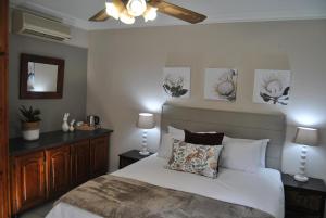 a bedroom with a bed and a ceiling fan at Hamilton Urban Farm Guest House in Pietermaritzburg