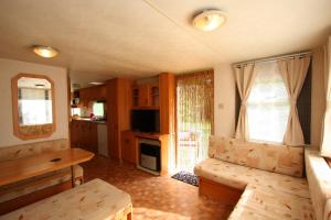 a living room with a couch and a table and a kitchen at Mobilhome Markgrafenheide für Familie und Monteure in Markgrafenheide