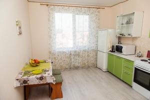a small kitchen with a table and a refrigerator at Apartment on Kukolkina in Voronezh