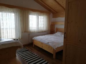 a bedroom with a bed and two windows at Pensiunea L`Amoro in Neagra Şarului