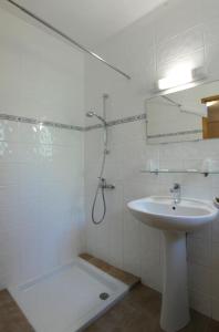 a white bathroom with a sink and a shower at HOTEL RESTAURANT LES STALAGMITES in Orgnac-lʼAven