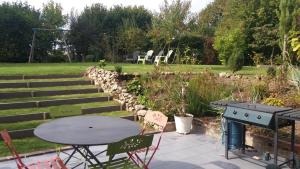 a patio with a table and chairs and a grill at LA RENAUDIERE in Dancé