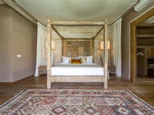 a bedroom with a canopy bed with a rug at Mannao Estate by Villa Finder in Kerobokan