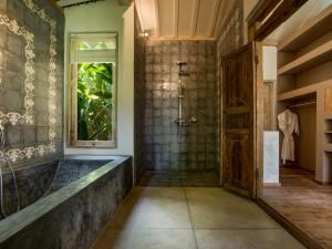 a bathroom with a tub and a window at Mannao Estate by Villa Finder in Kerobokan