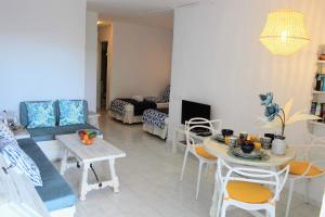 uma sala de estar com um sofá, uma mesa e cadeiras em Bougainvillea apartment Bamira em Maspalomas