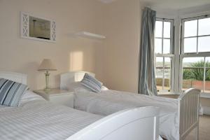 two beds in a white room with a window at Michaelstow in Perranporth