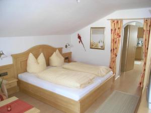 um quarto com uma cama com lençóis brancos e almofadas em Gästehaus Auerstüble em Balderschwang