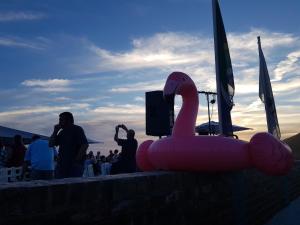 a inflatable pink swan sitting on a wall with people at Pili Pili Beach Cabanas in Sedgefield