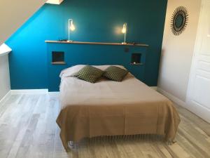 1 dormitorio azul con 1 cama con 2 almohadas en La Petite Mer, en Riantec