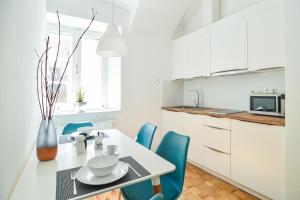 eine weiße Küche mit einem Tisch und blauen Stühlen in der Unterkunft Ljubljana Center Apartments in Ljubljana