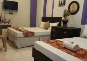a hotel room with two beds and a tv at Center Parkway Pension House in Kalibo