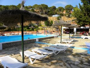 a group of chairs and umbrellas next to a swimming pool at Camping Sènia Cala Canyelles in Lloret de Mar