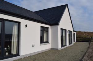 una casa bianca con tetto e finestre neri di Dunarain Bed & Breakfast a Tarbert