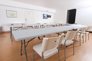 a classroom with white tables and white chairs at Hôtel Le Leukos in Leucate