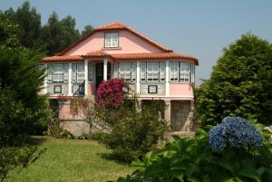 una casa rosa con ventanas y flores en el patio en Quinta do Vale do Monte en Viana do Castelo