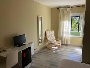 a living room with a chair and a television at Pension Antonio in Louro