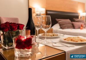 uma mesa com copos de vinho e rosas em cima em Motel Portofino em Matosinhos