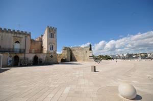 a large courtyard with a building and a tower at Appartamenti porta mare in Otranto