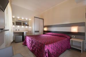 Un dormitorio con una cama rosa y un escritorio. en Hotel Siena, en Verona