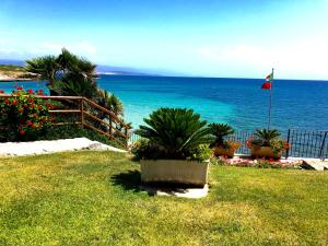 a view of the ocean with plants and a flag at Hotel Punta Negra in Alghero