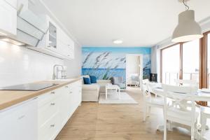 a kitchen with white cabinets and a dining room at Jantar Apartamenty - Beach Resort in Kołobrzeg